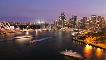 Captivating view of Sydney's illuminated skyline with the iconic Opera House and harbor at night.